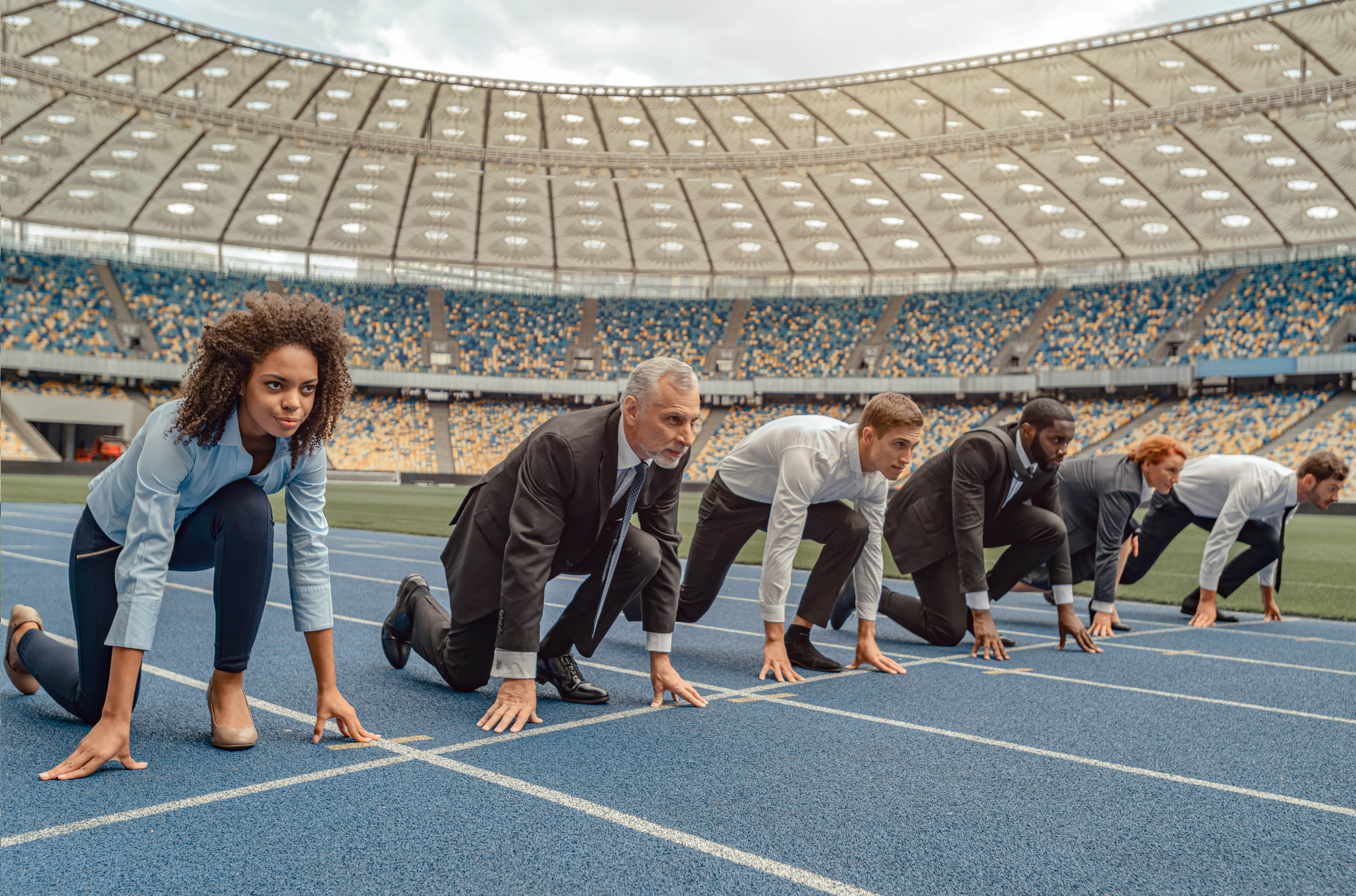 Businessmen and women standing at the starting line on a race track in a stadium Businessmen and women standing at the starting line on a race track in a stadium
